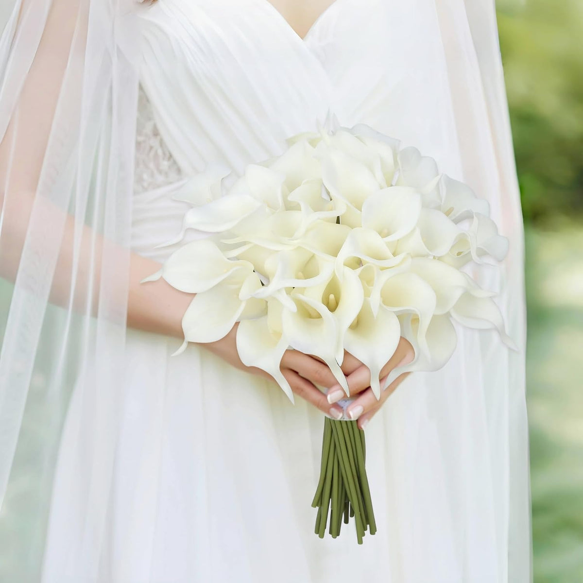 Bride holding a bouquet of white flowers with a blurred green background