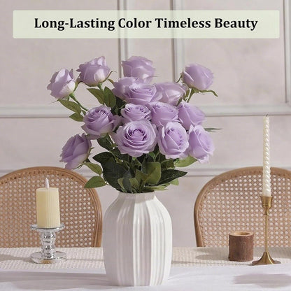 Bouquet of purple roses in a white vase on a table with candles and a neutral background.