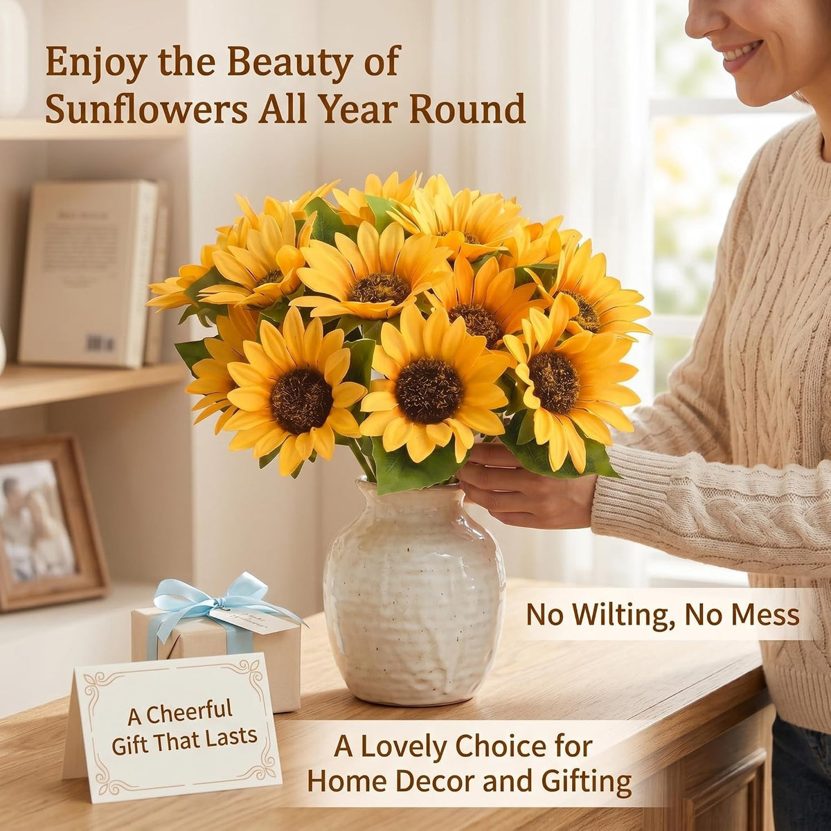 A person in a beige sweater holds a bouquet of bright yellow artificial sunflowers in a textured white vase on a wooden table. The scene includes promotional text overlays about the sunflowers and a small gift box with a blue ribbon.