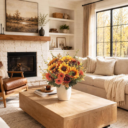 A styled living room featuring a large wooden coffee table in the foreground with a white vase of sunflowers, set in front of a beige sofa and a white brick fireplace.
