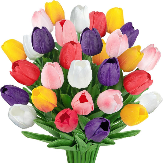 A vibrant bouquet of artificial tulips in multiple colors including yellow, red, pink, white, and purple, with green stems and leaves, isolated on a white background.