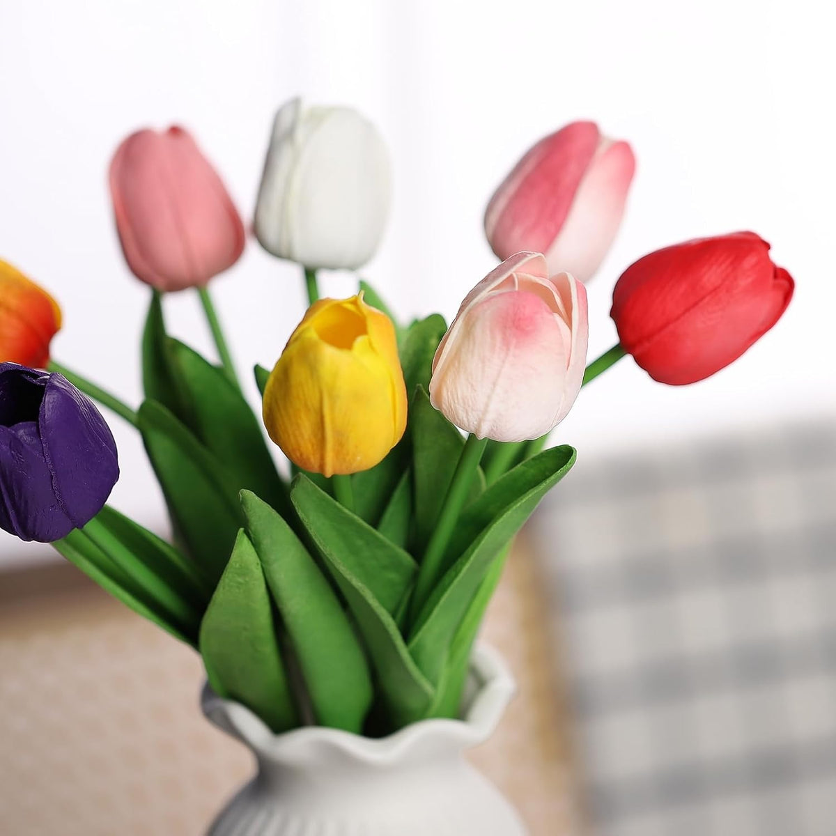 Colorful tulips in a white vase on a blurred background